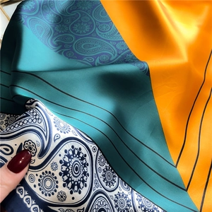 Close-up of silk scarf showing paisley patterns and geometric color blocks with glossy texture