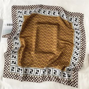 Macro detail of luxury square scarf featuring vintage monogram patterns and brown tones
