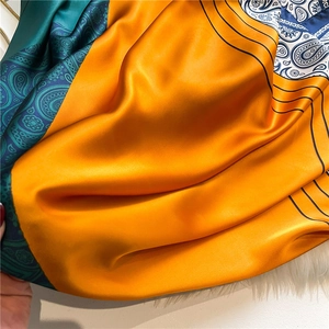 Close-up of silk scarf showing glossy paisley patterns and vibrant orange color