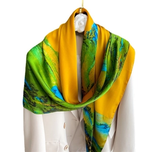 Artistic landscape silk scarf with vibrant yellow and green prints on a white blazer