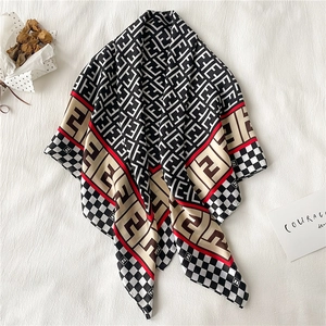 Detail of luxury silk scarf showing checkerboard patterns and monogrammed contrast edges