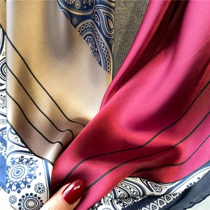 Close-up of silk scarf with paisley patterns and burgundy color block design
