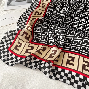 Macro shot of houndstooth scarf with logo print and red border on textured fabric