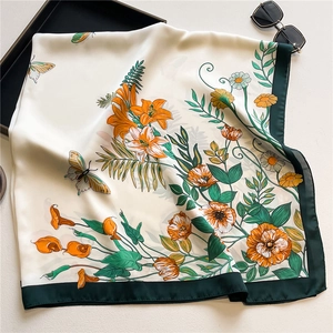 Detailed close-up of a 110cm silk scarf with floral patterns and a wide green border