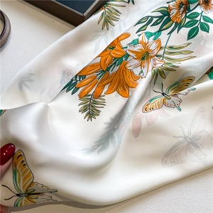 Close-up of silk scarf showing orange lilies and butterfly prints with satin luster