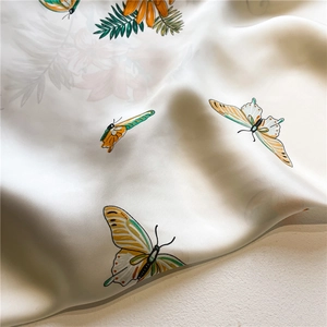 Detail of silk scarf showing realistic butterfly prints and glossy satin fabric texture