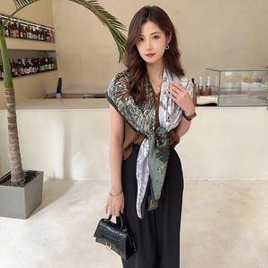 Detail of silk scarf with tropical leaf pattern and bird print in urban cafe setting