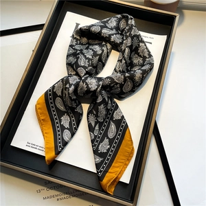 Détail d'un foulard en soie de luxe avec motif paisley et accents jaune moutarde