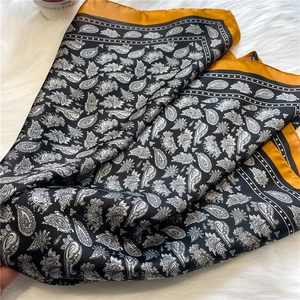Gros plan du foulard en soie noir à motif cachemire avec bordure jaune moutarde