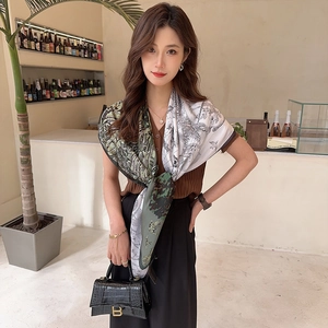 Detail of silk scarf with green and white floral pattern worn by a model in a cafe
