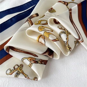 Detail of silk scarf with equestrian prints and golden bit motifs in elegant folds