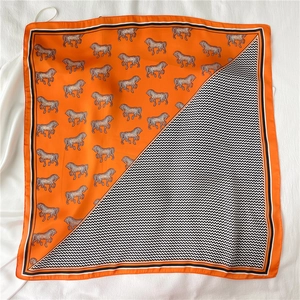 Dettaglio foulard di seta con stampe di cavalli arancioni e motivi a zigzag