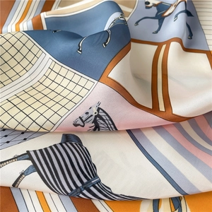 Detail of silk scarf with equestrian horse print and geometric patterns in orange and blue