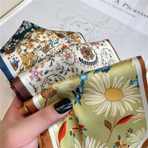 Gros plan de foulards en soie aux imprimés floraux et ourlet roulé avec un livre