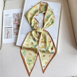Détail d'un foulard étroit en soie à imprimé marguerites blanches sur fond vert