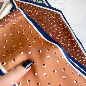 Détail de la texture du foulard en soie avec pois blancs et ourlet contrasté bleu