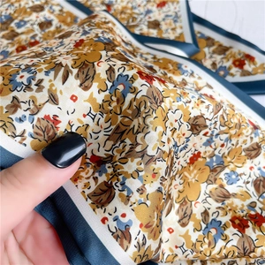 Détail d'un foulard en soie à fleurs montrant la texture satinée et les bords bleus
