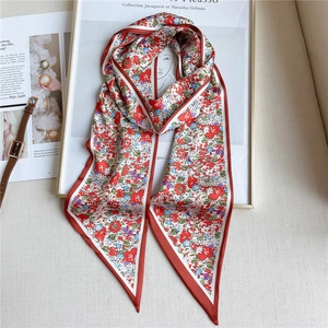 Détail d'un foulard étroit en soie à fleurs rouges avec une montre et un cadre chic