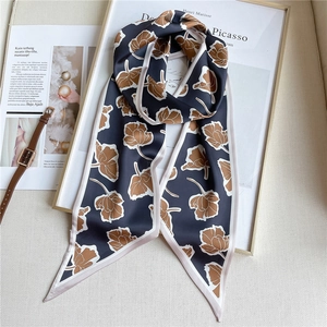 Vue détaillée d'un foulard long en satin bleu marine avec motifs floraux et bordure blanche