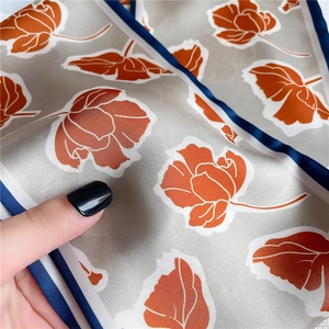 Détail macro d'un foulard en soie gris avec tulipes orange et bordure bleu marine