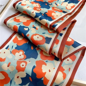 Détail d'un foulard en soie aux fleurs orange et aux motifs bleus élégants