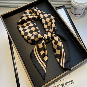 Detail of silk-like square scarf with black and gold checkered pattern in an elegant setting
