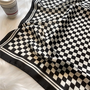 Elegant black and white checkerboard silk-like scarf on soft plush background texture
