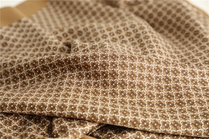 Macro detail of retro patterned silk fabric with elegant brown and white floral monogram print