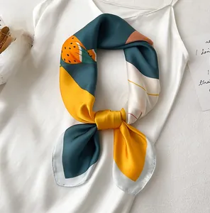 Carré de soie aux motifs d'oiseaux noué élégamment comme accessoire sur une robe blanche