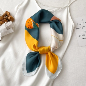 Détail d'un foulard en soie à motif d'oiseau noué sur un col de robe blanche