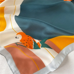 Détail d'un foulard en soie montrant un motif d'oiseau abstrait et une texture lisse