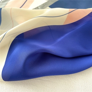 Détail du foulard en soie à motif d'oiseaux montrant une texture lisse et des blocs bleus