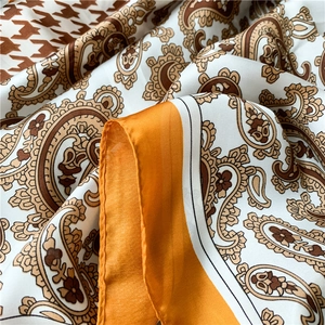 Detail of silk-like scarf showing paisley and houndstooth patterns with orange borders