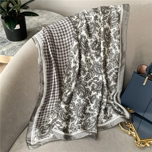 Detail of long silk scarf with classic paisley and houndstooth pattern on velvet sofa