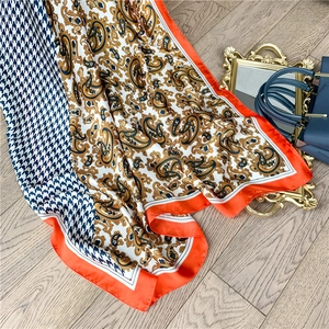 Long faux silk scarf featuring houndstooth and paisley prints with orange borders