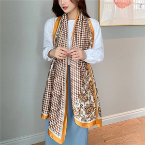 Detail of silk satin scarf featuring houndstooth and paisley prints with yellow edges