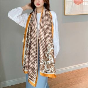 Detail of long silk-like scarf with houndstooth and paisley print draped on a model
