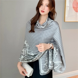 Detail of elegant gray houndstooth and paisley silk-like scarf draped on a model