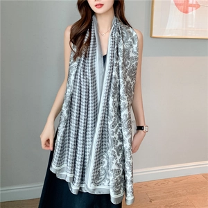 Detail view of a long faux silk scarf featuring houndstooth and paisley patterns in silver grey