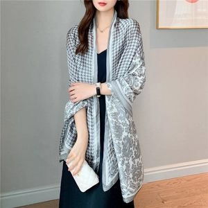 Detail of silk-like long scarf featuring houndstooth and paisley patterns in grey and white