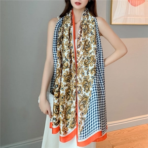 Detail showing vintage paisley and houndstooth patterns on a silky long scarf with orange trim