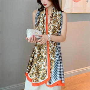 Detailed view of paisley and houndstooth pattern patchwork on a long silk-feel scarf