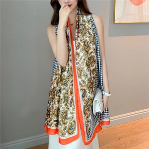 Detail of silk-like long scarf featuring paisley and houndstooth patterns with orange edges