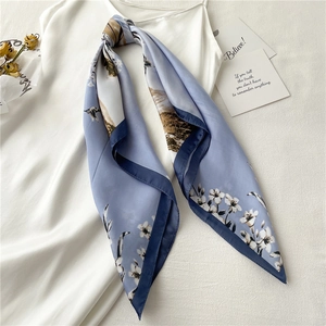 Elegant blue and white floral silk scarf styled on a white dress with mountain scenery print
