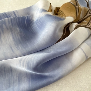 Detail of silk scarf showing soft fabric folds and artistic blue floral pattern