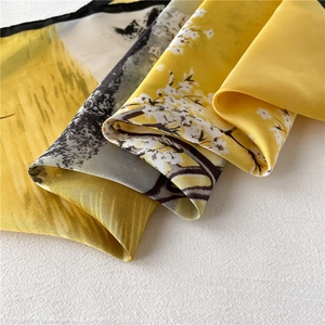 Macro detail of bird and floral pattern on yellow silk scarf with fine black hemmed edges