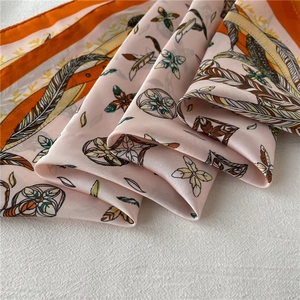 Close-up of pink and orange silk scarf with feather and floral prints and silky folds
