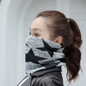Gros plan du cache-cou en tricot à motifs d'étoiles gris et noir porté comme masque