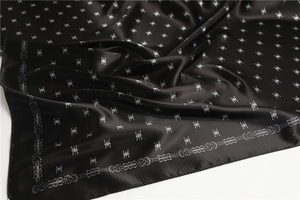 Dettaglio del foulard in raso nero con eleganti motivi argentati e lucentezza della seta