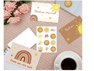 Flat lay of boho thank you card set with rainbow sun illustrations on pink knit background